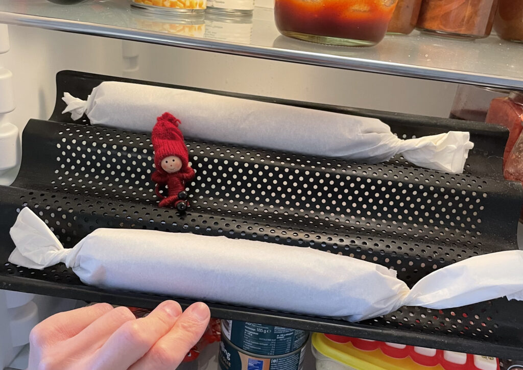 ro ruller brunkagedej og en lille nisse på en baguetteform i køleskabet